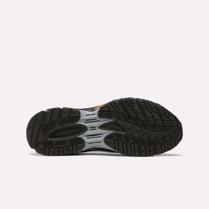 The image displays the black rubber outsole of the Reebok Premier Road Ultra SV Running Shoes, showcasing detailed tread patterns and grooves engineered for traction, with subtle gray and orange accents along the midsole that emphasize its retro-inspired sneaker design.