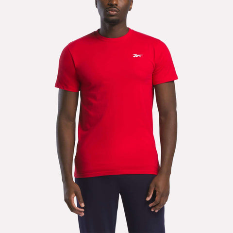 A person wearing a bright red Reebok Men's Small Logo T-Shirt and dark pants stands against a plain white background.