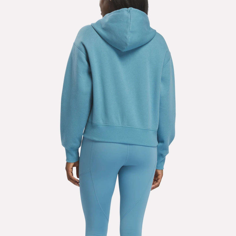 A person is seen from the back wearing a Reebok Women's Cropped Full-Zip Hoodie and matching light blue leggings against a plain white background.