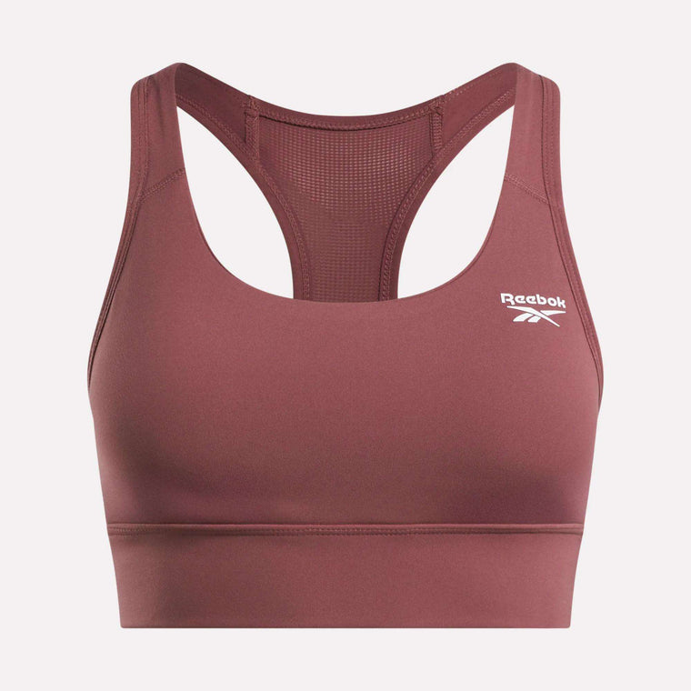 The Reebok Women's Rush Medium-Impact Sports Bra in mauve features a racerback design, mesh back panels for breathability, and a white logo on the front—perfect for medium-impact workouts.