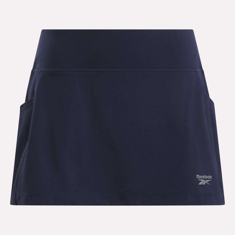 The Women's Break Point Skort by Reebok is a navy blue training skort featuring side pockets, built-in compression shorts, and a small logo on the lower right, shown against a light background.