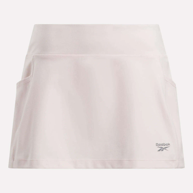 The Reebok Women's Break Point Skort is light pink, features built-in compression shorts, a wide waistband, two side pockets, and the Reebok logo near the right bottom hem.