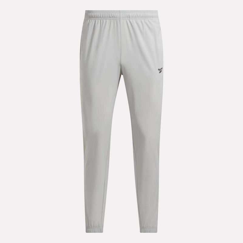 Men’s Repeat Pants by Reebok in light gray, designed with an athletic tapered fit, elastic waistband and cuffs, and a small black Reebok logo on the upper left thigh, displayed against a plain white background.