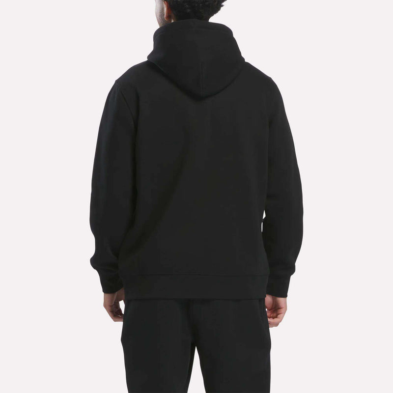 A person is shown from the back wearing the Reebok Men’s Patent Hoodie in black with an embroidered logo and black pants, standing against a plain light background.