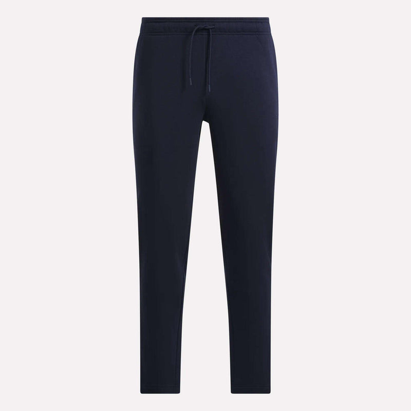Reebok Men’s Patent Pant in navy blue, made from soft knit fabric, features an elastic waistband with drawstring and tapered legs, shown against a plain light background.