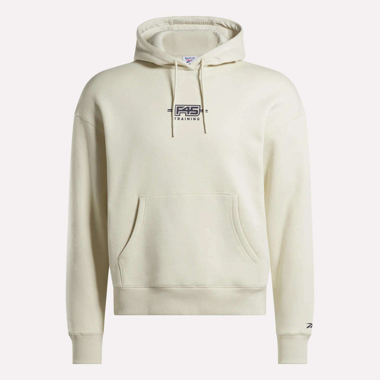 The Reebok x F45 Training Relaxed Fleece Hoodie by Reebok features a cream-colored fleece, relaxed fit, front pocket, black F45 Training logo on the chest, and a small logo on the left sleeve near the wrist.