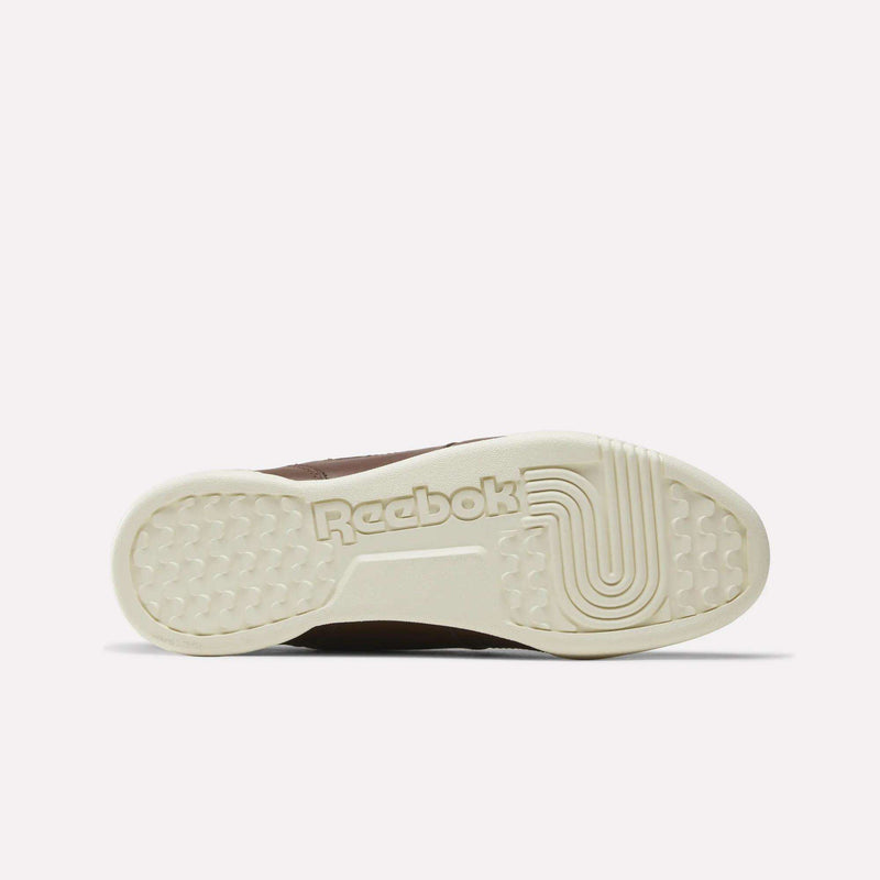 The image features the sole of a beige Reebok Workout Plus Shoe, showcasing the Reebok logo and a textured grip pattern set against a plain white background. Drawing inspiration from the iconic Workout Plus design, this shoe blends heritage style with dependable traction.