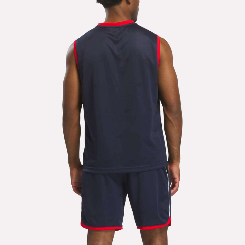A person wearing a Reebok Men's United Jersey Tank in navy blue and matching shorts with red trim stands facing away from the camera against a plain background.
