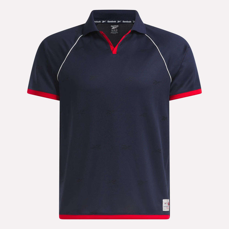 The Reebok Men's United Jersey Polo Shirt is navy blue with red trim on the collar, sleeves, and hem, white piping on the shoulders, and a small Reebok logo tag—a stylish addition to any men's sports jersey collection.
