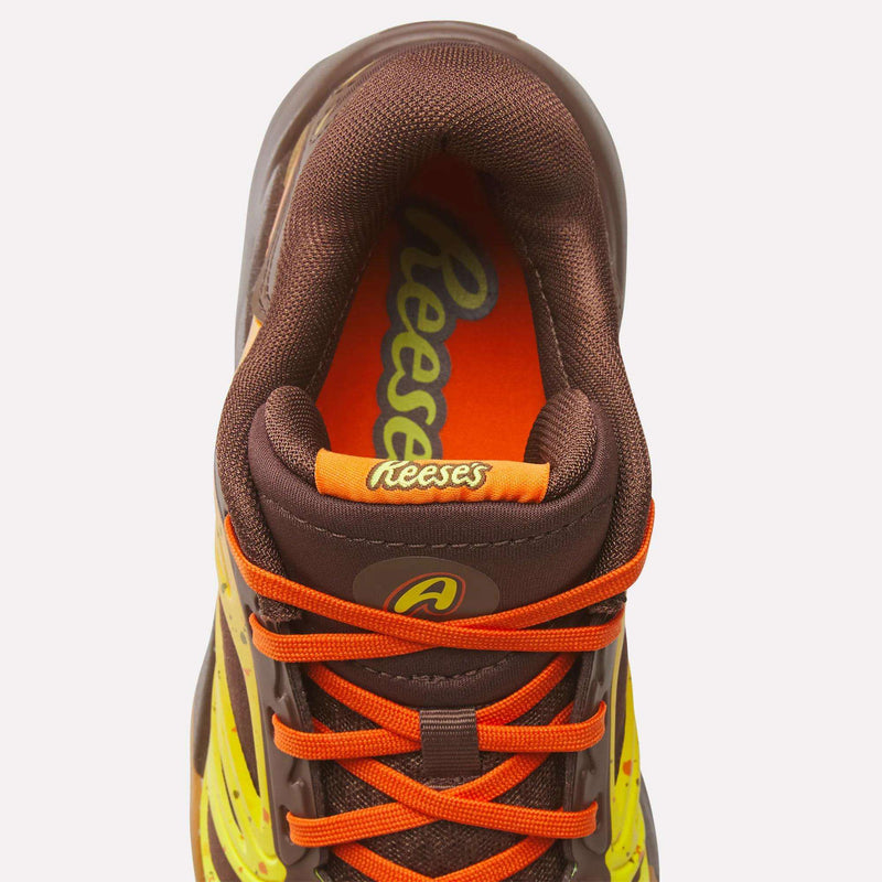 Top view of a brown and yellow Reebok Reese’s x Angel Reese 1 Basketball Shoe for Big Kids with orange laces, featuring Reese’s branding on the insole and tongue, inspired by Reese’s peanut butter cups. This collaboration between Reebok and Reese’s delivers standout style and performance innovation for kids on and off the court.