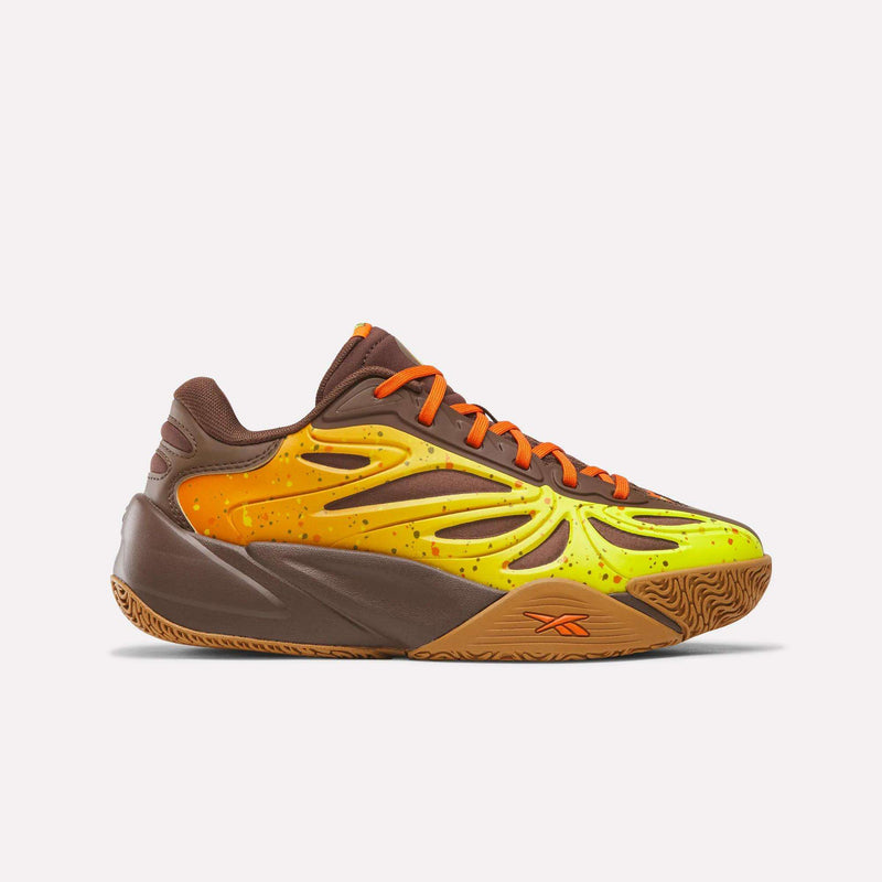 The Reebok Reese’s x Angel Reese 1 Basketball Shoes for big kids are shown on a plain white background, featuring a brown, orange, and yellow color scheme with yellow flame-inspired accents, orange laces, and a chunky sole—highlighting performance-driven design inspired by basketball innovation.