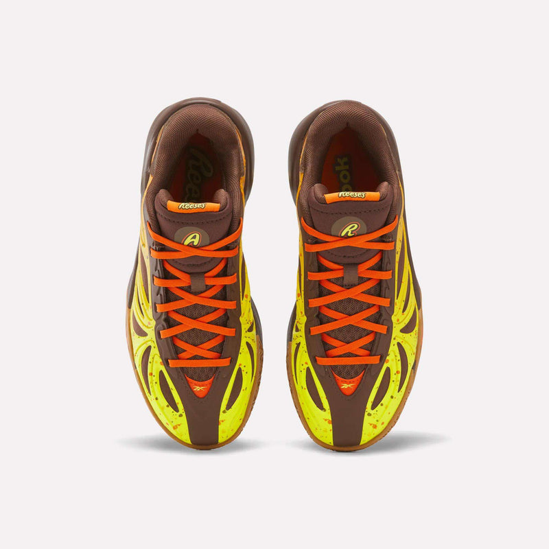 Top view of a pair of Reebok Reese’s x Angel Reese 1 Basketball Shoes for Big Kids, featuring brown and neon yellow uppers, orange laces, and black accents, placed side by side on a white background.