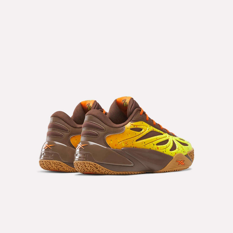 A pair of Reebok Reese’s x Angel Reese 1 Basketball Shoes in brown, yellow, and orange with a wavy pattern, speckled details, textured soles, and an advanced Energy Return System, displayed on a white background.