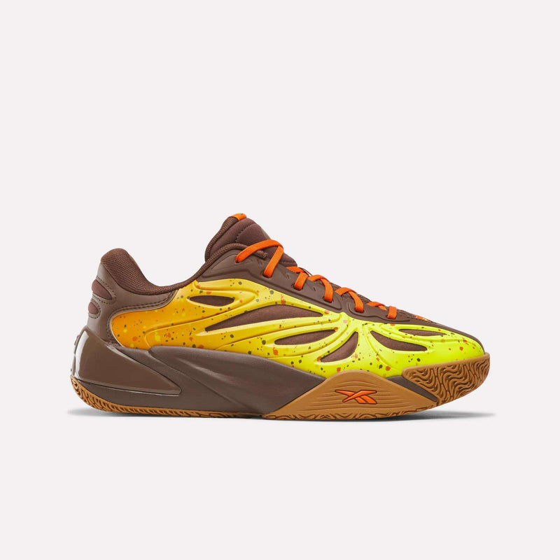 The Reese’s x Angel Reese 1 Basketball Shoes by Reebok feature a brown, orange, and yellow colorway with orange laces and a striking yellow, flame-inspired design on the side. Speckled details and a textured gum sole add unique flair, while the Reebok logo near the heel highlights their athletic style—drawing inspiration from signature Angel Reese sneakers.