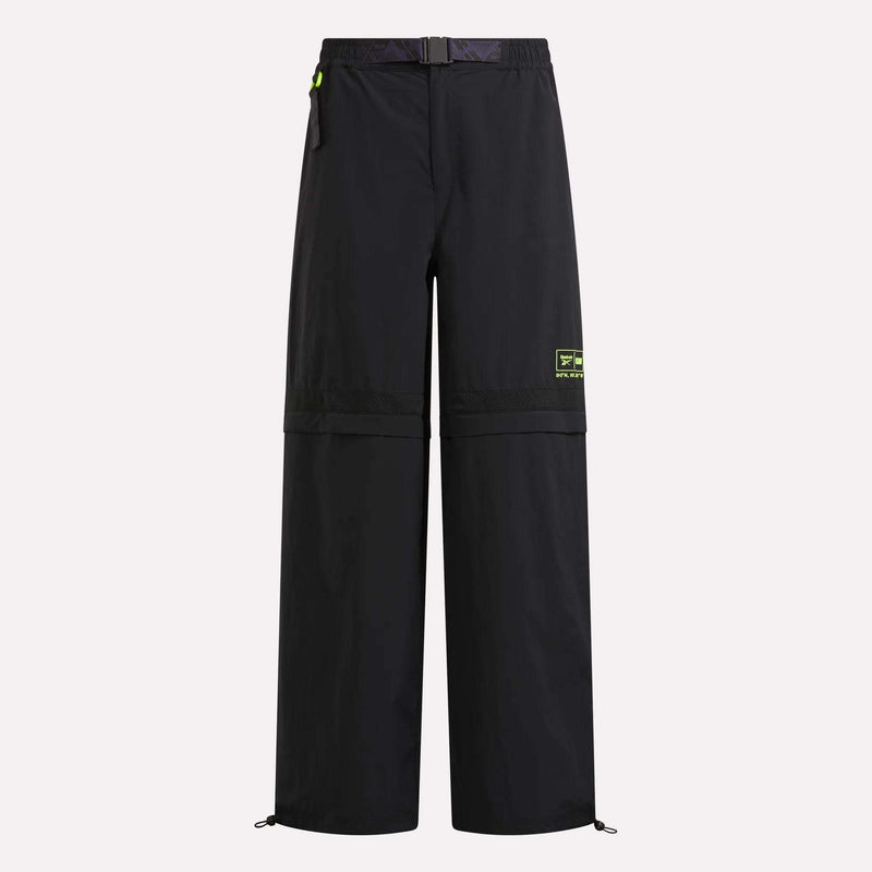 Black Reebok x A Herd of Bison Transform Pants featuring a buckled waist belt, neon green accents, and zip-off legs at the knees.