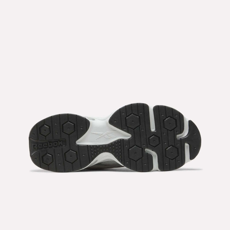 The image displays the black and white rubber sole of the Men’s Charge Shoes by Reebok, viewed from below and showcasing hexagonal patterns along with the Reebok logo. Engineered for performance, these training shoes provide enhanced grip and stability—making them a reliable choice for workouts, with a cushioned midsole to ensure added comfort.