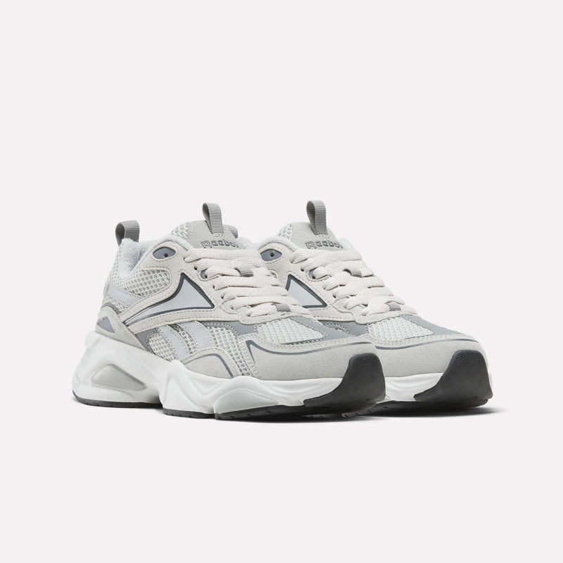 A pair of Reebok Men’s Charge Shoes in light gray and white, featuring mesh and suede details, thick white soles with a cushioned midsole, and lace-up fronts, displayed on a plain white background.