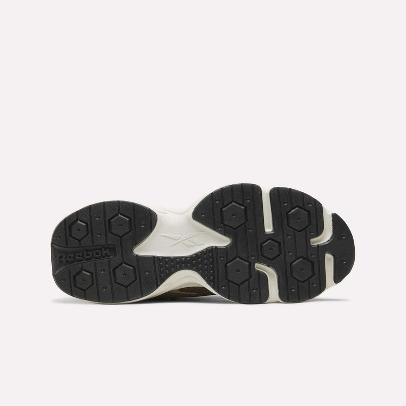 The image shows the black and white rubber sole of the Reebok Men’s Charge Shoes, photographed from the bottom against a plain white background. The Reebok logo is visible on the left side of the sole, highlighting classic design details inspired by heritage styles.