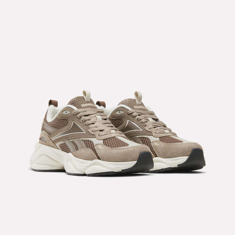 A pair of Reebok Men’s Charge Shoes in beige and brown, featuring heritage-inspired design with mesh and suede uppers, white midsoles, and black outsoles, displayed against a plain white background.