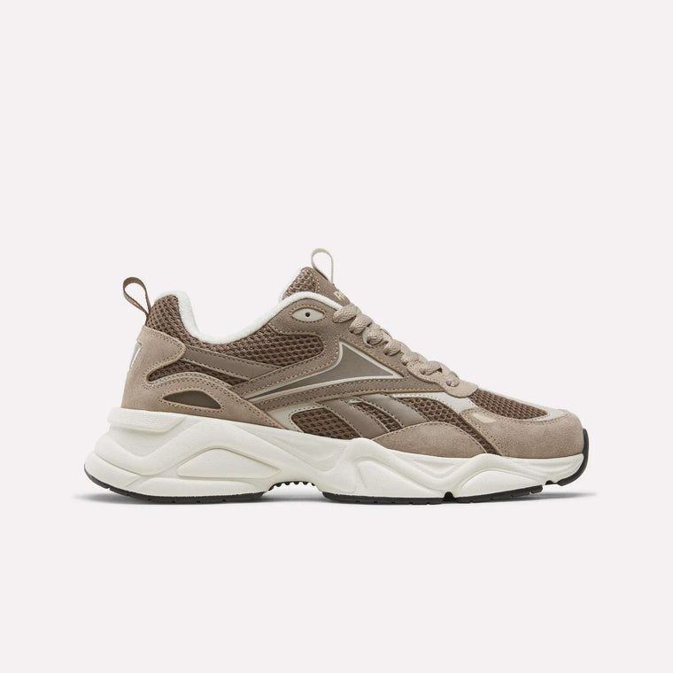 The Reebok Men’s Charge Shoes in brown feature mesh and suede panels, beige and white detailing, a chunky white sole, and black tread. Shown from the side on a plain white background, these heritage-inspired sneakers blend timeless style with modern performance for men seeking versatile training footwear.