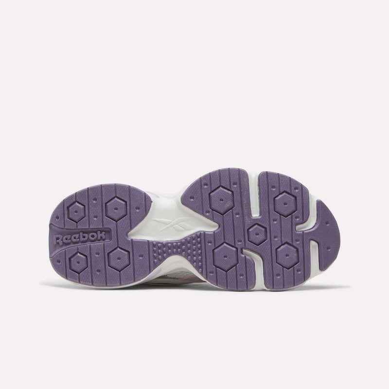The image displays the bottom view of the Women’s Charge Shoes by Reebok, featuring a purple sole with hexagonal patterns and the Reebok logo embossed on the left side. The cushioned midsole is designed for enhanced comfort, making these shoes perfect for training.