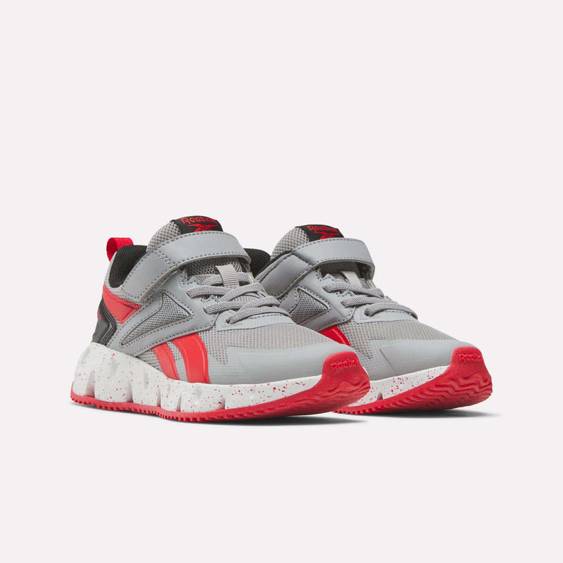 A pair of Reebok Pyro Storm 1V Shoes for little kids in gray and red, featuring mesh uppers, velcro straps, laces, and white speckled soles. The athletic shoes are displayed side by side on a light background, angled slightly forward.