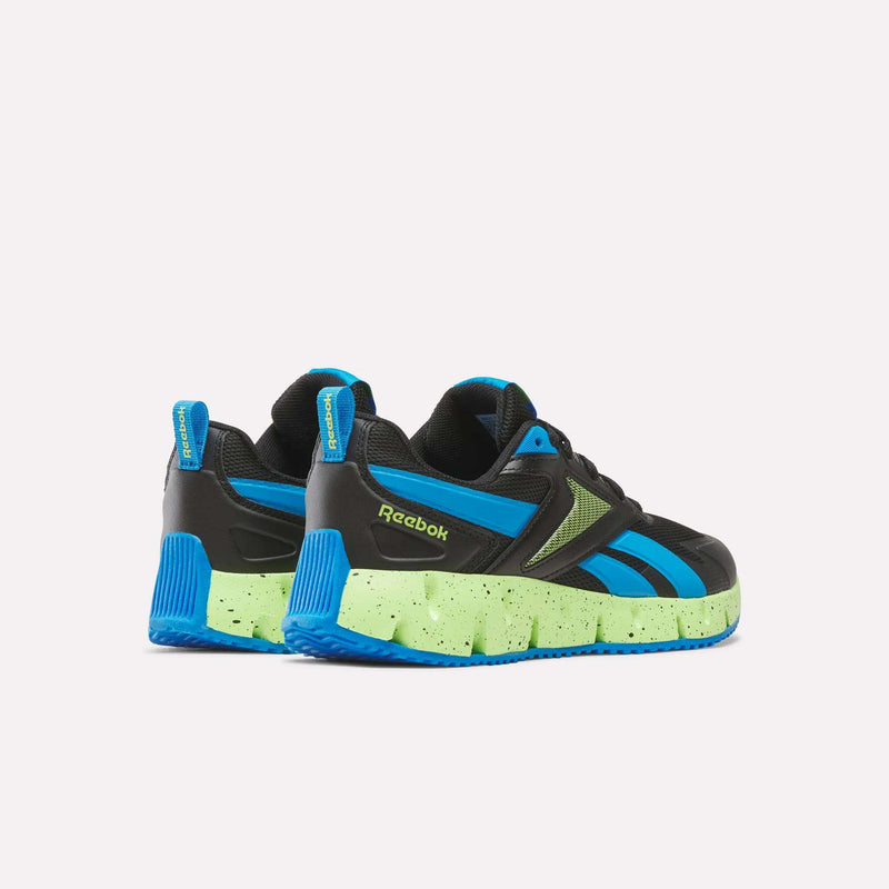The Reebok Pyro Storm 1V Shoes - Little Kids feature black uppers, blue accents, and bright green speckled soles set against a white background. Built with a durable rubber outsole, these athletic shoes deliver both stylish looks and long-lasting performance for kids.