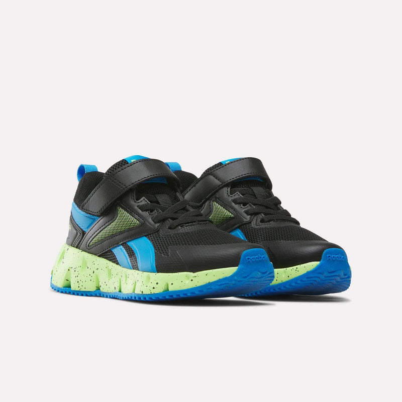 A pair of Reebok Pyro Storm 1V Shoes for little kids, in black with blue and green accents, featuring Velcro straps, mesh panels, a neon green speckled sole, and durable rubber outsoles, displayed on a white background.