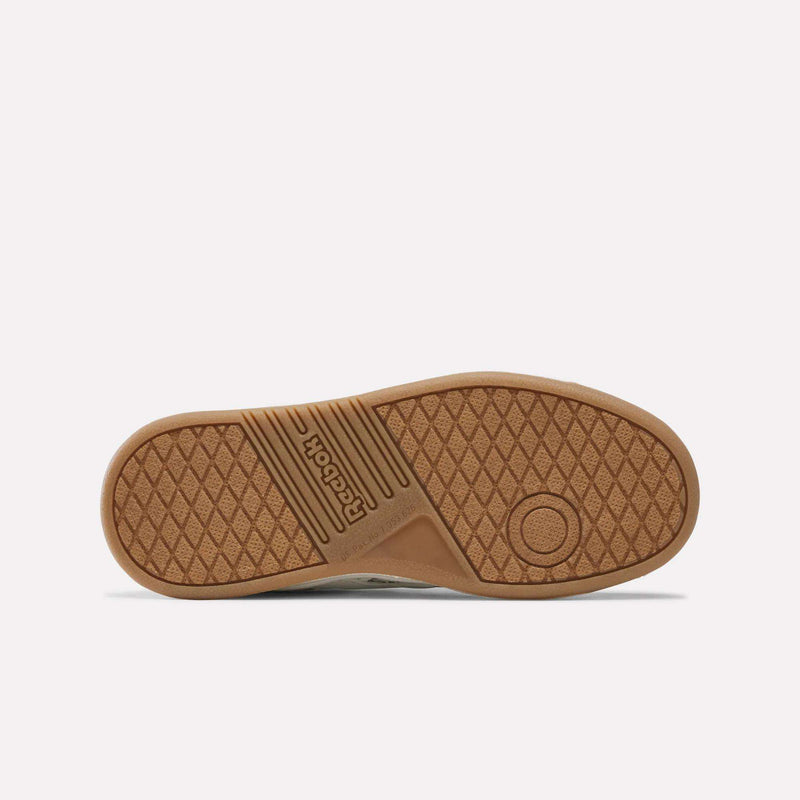 Bottom view of a brown rubber sole from the Reebok Forte Pitch Shoes - Big Kids, featuring a textured diamond pattern, circular tread detail, and the Reebok logo embossed near the midfoot for a court-inspired look.
