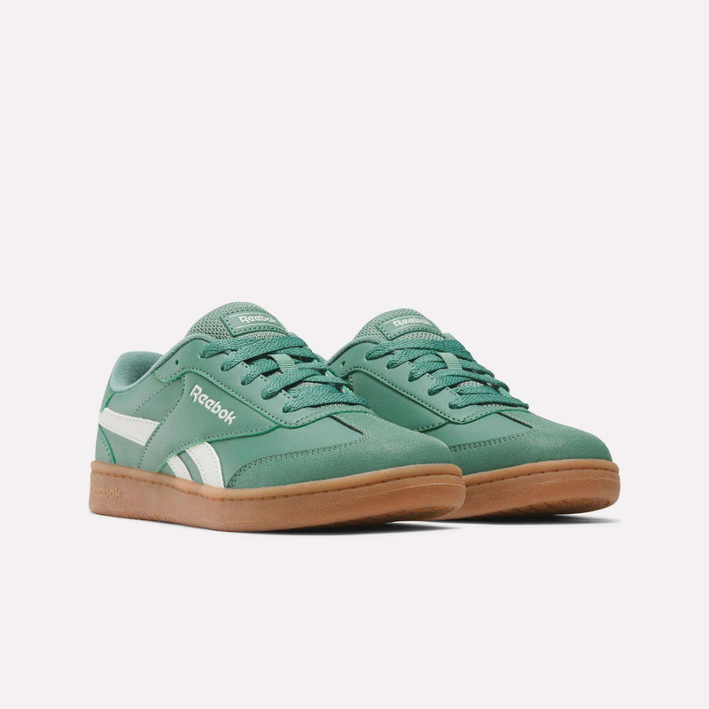 A pair of Reebok Forte Pitch Shoes - Big Kids in green, featuring white side stripes and gum-colored soles, displayed against a plain white background.