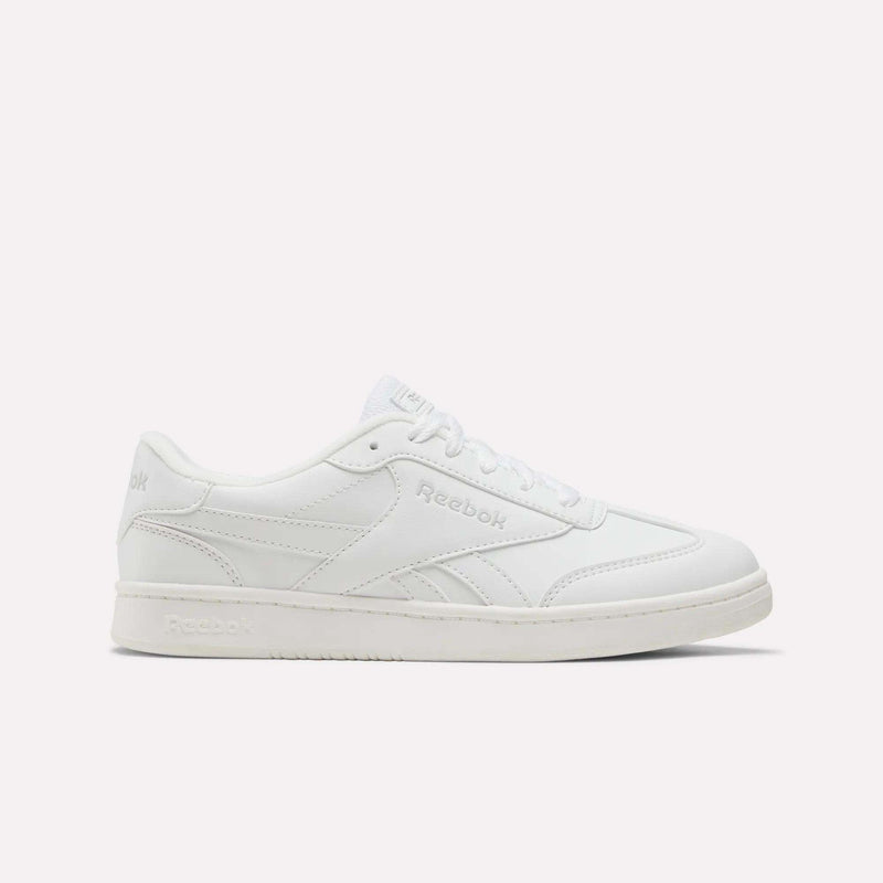 A white Reebok Forte Pitch Shoe for big kids, featuring a low-top silhouette, lace-up closure, and subtle stitched accents is displayed from the side against a plain light backdrop—a contemporary update on court-inspired footwear.