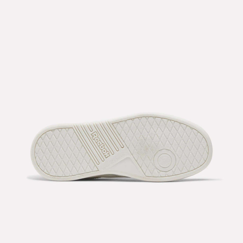The image displays the white sole of the Reebok Forte Pitch Shoes - Little Kids, showcasing a diamond-patterned tread, a circular detail on the right side, and central Reebok branding—a subtle homage to its tennis-inspired design.