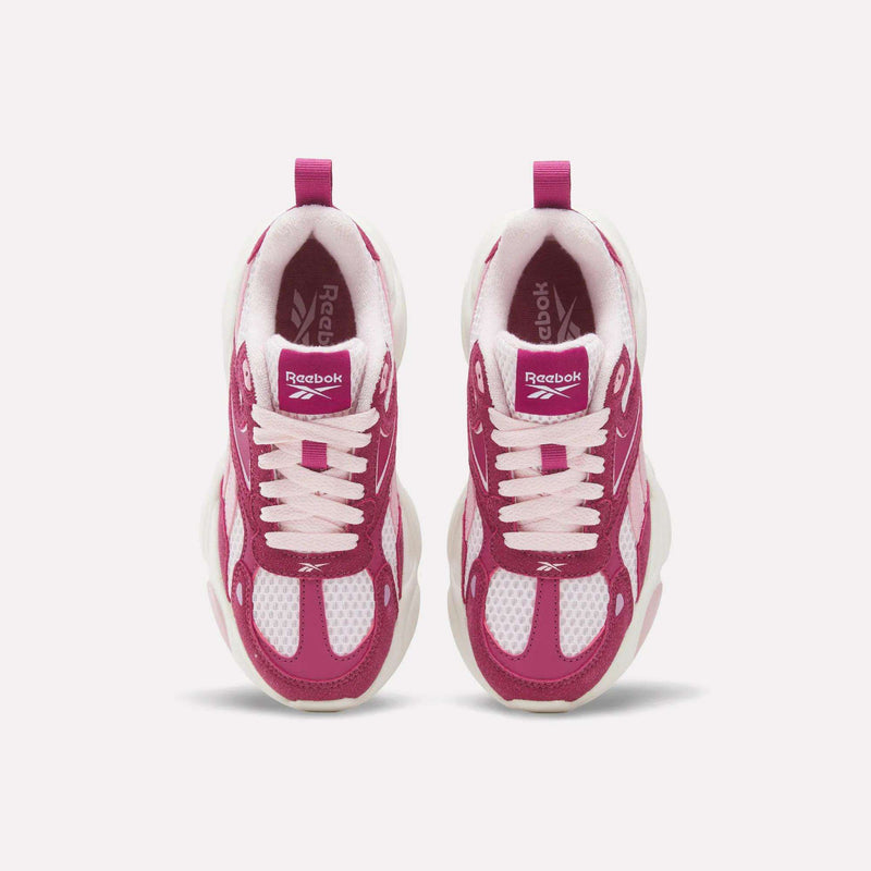Pair of little kids’ Reebok Charge Shoes in magenta and white with white laces and chunky soles.