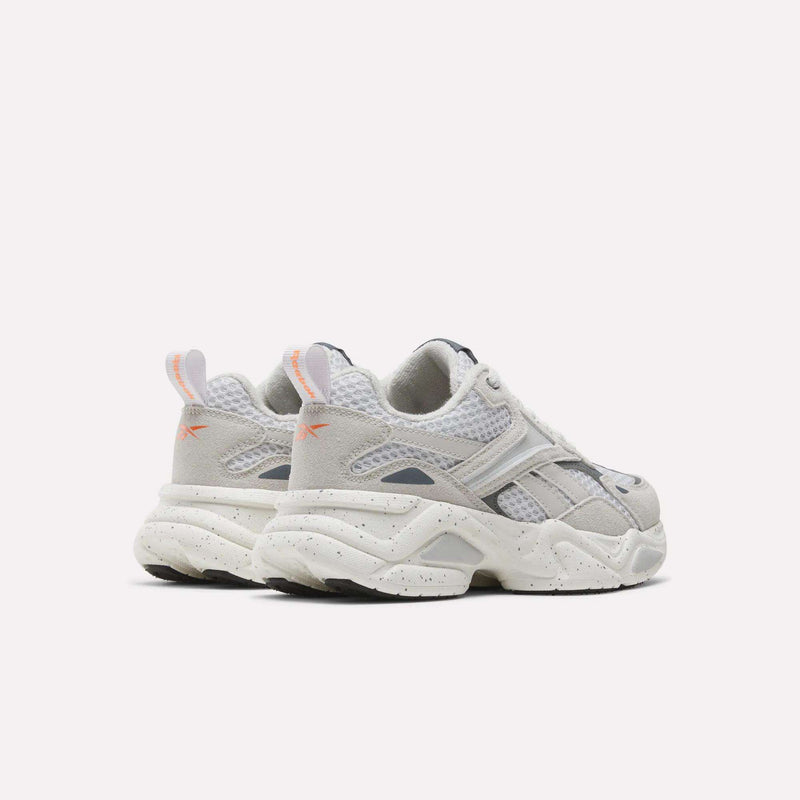 Rear three-quarter view of Charge Shoes - Little Kids in white, grey, and orange, featuring chunky, speckled outsoles and a cushioned design.