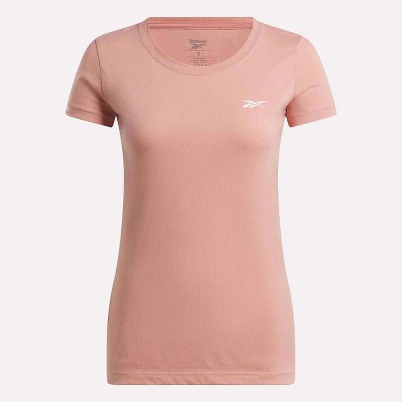 The Reebok Women's T-Shirt features a plain light pink cotton design with short sleeves, a round neckline, and a small white Reebok logo on the left chest, shown against a white background.