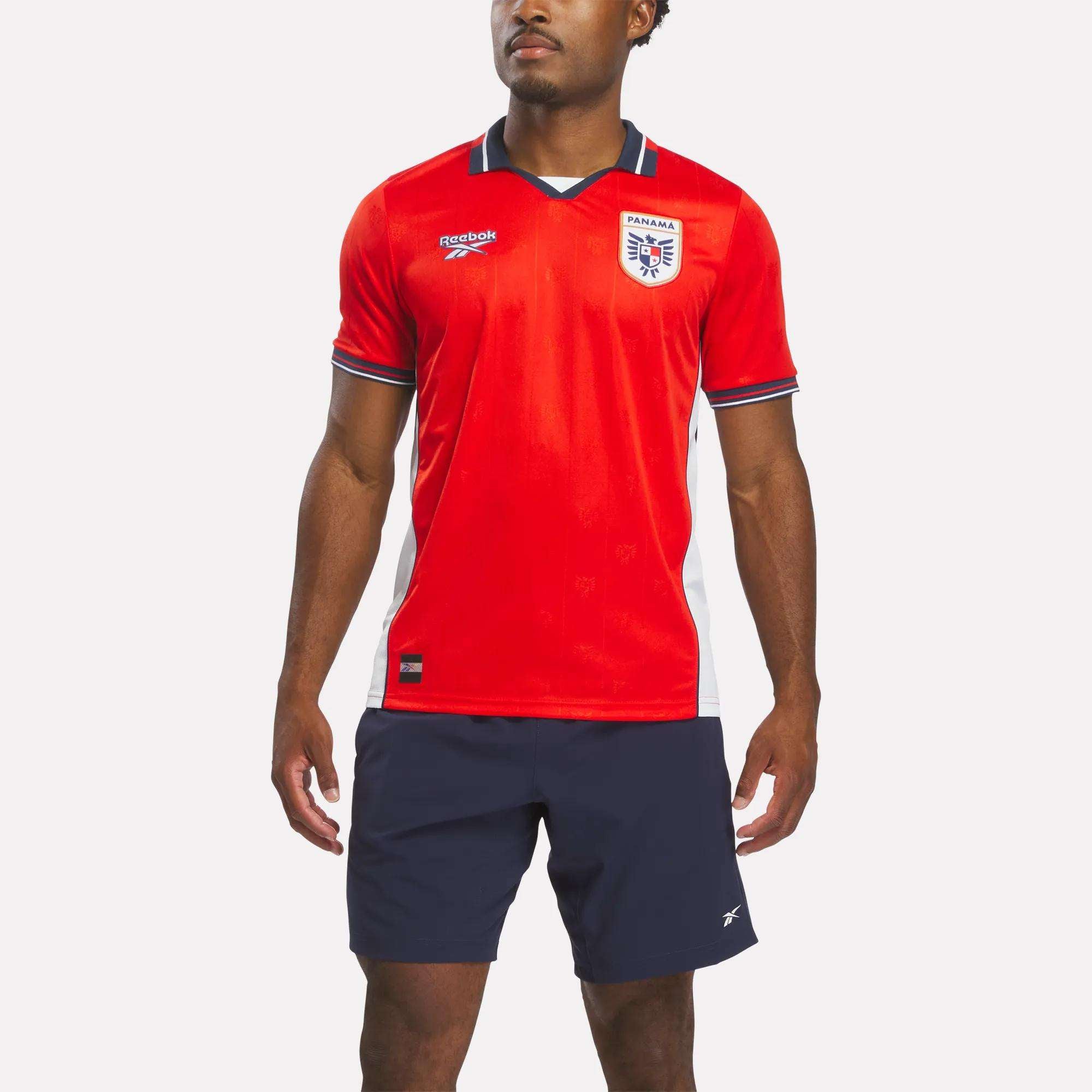 A person wearing a red Reebok Men's Panama Home Jersey stands against a plain white background.