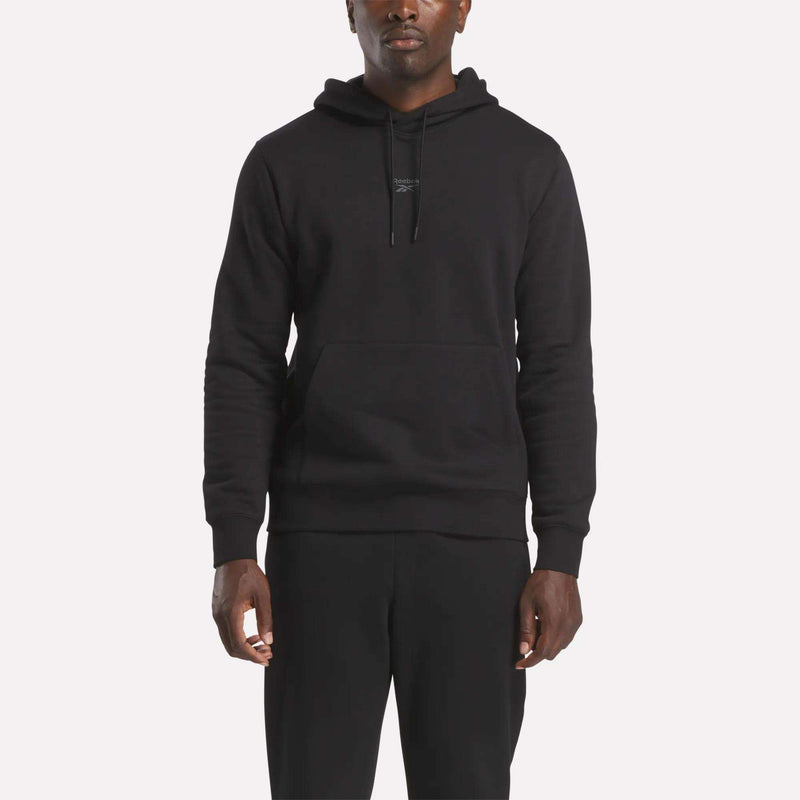 A person wearing a comfortable Reebok Men’s Finisher Hoodie in black stands facing forward against a light background.