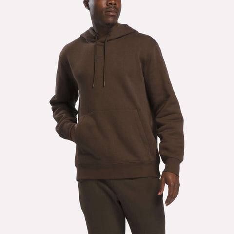 A man wearing the Reebok Men’s Finisher Hoodie, featuring a front pocket, along with matching brown pants stands against a plain white background.