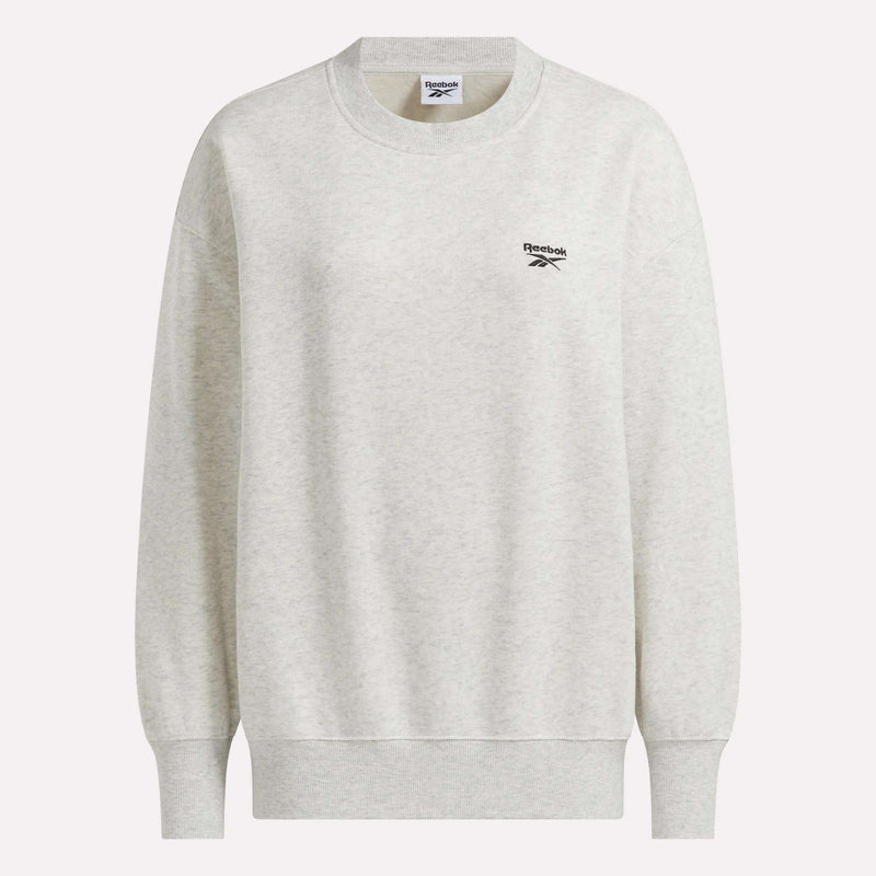 Reebok Women’s Oversized Crewneck Sweatshirt in light grey, featuring long sleeves, ribbed cuffs and hem, and a small black Reebok logo on the left chest. This comfortable crewneck is perfect for everyday wear.