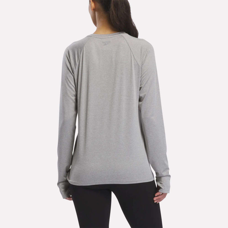 A woman with a ponytail wears a Women’s Long Sleeve Running Top by Reebok and black leggings, shown from the back against a plain white background.