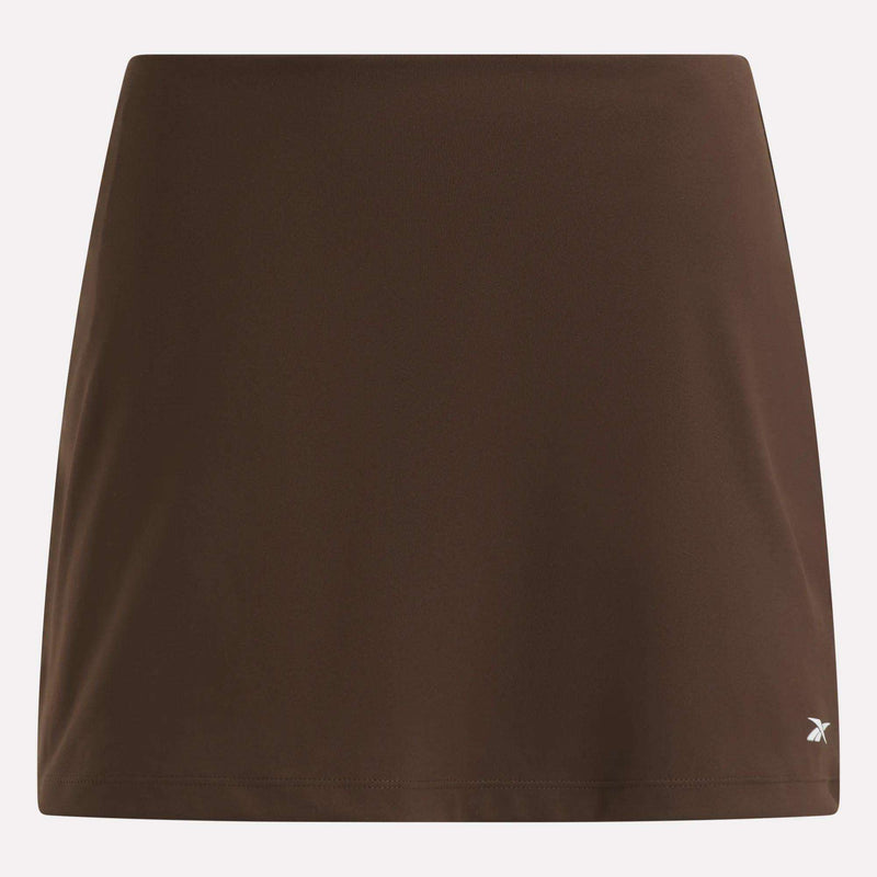 Displayed against a light background, the Reebok Women’s Tennis Skort features a plain brown design with a small white logo near the bottom right hem, embodying classic court-inspired style.