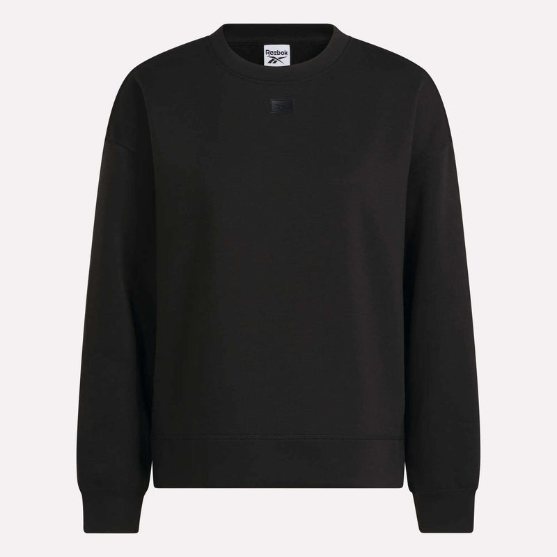 Introducing the Women’s Crewneck Sweatshirt by Reebok—a classic black sweatshirt with long sleeves, ribbed cuffs and hem, and a discreet Reebok logo patch on the chest. Made from soft doubleknit fabric, this women’s sweatshirt is shown against a light background.