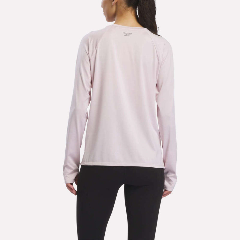 A woman is shown from the back against a white background, wearing a Women’s Long Sleeve Running Top by Reebok in light pink, paired with black leggings.