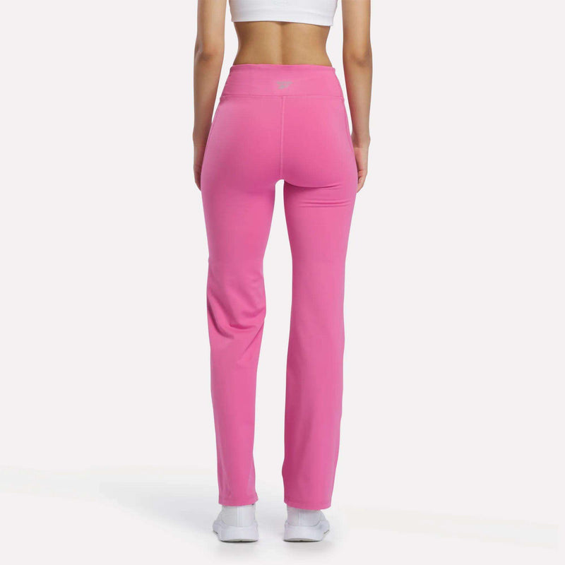 Back view of a person wearing bright pink Reebok Women’s Highstreet High-Rise Pants and white sneakers.