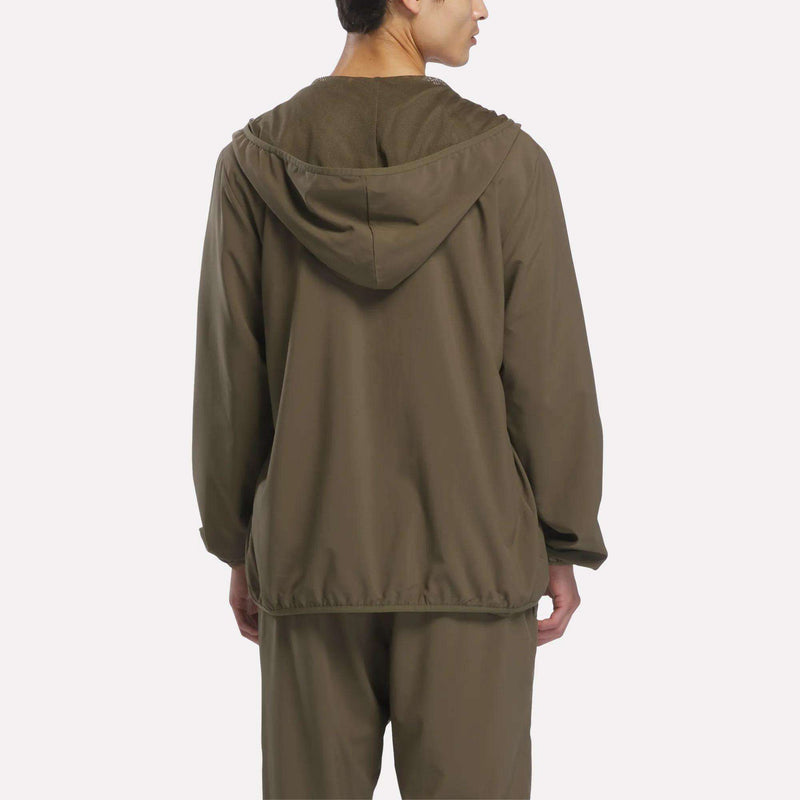 Back view of a person wearing an olive green Men’s Woven Jacket by Reebok and matching pants.