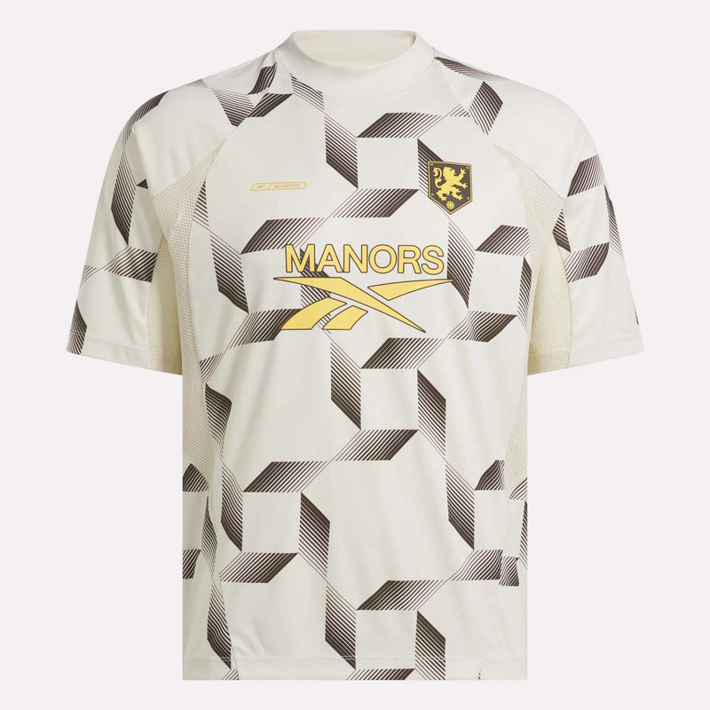 Introducing the Reebok x Manors Men’s Mockneck Polo: a white jersey featuring a bold geometric black pattern, gold MANORS lettering, a gold logo, and a lion crest on the left chest. Designed from performance stretch fabric for exceptional comfort and mobility, this exclusive piece is part of the coveted Reebok x Manors collection.