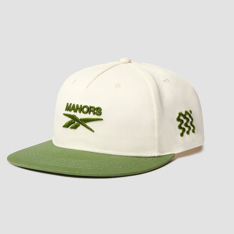 Introducing the Reebok x Manors Men’s Retro Crown Cap: This cream-colored cap features a green brim, MANORS and leaf embroidery on the front, and a wavy green line detail on the side. Designed with an adjustable snapback closure for a personalized fit, its retro crown adds classic style to this standout accessory from Reebok.