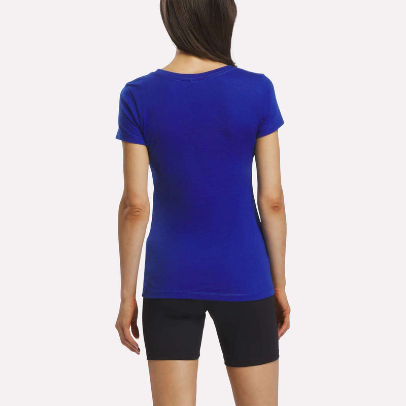 A person with long brown hair is seen from behind wearing the Reebok Women’s Logo Tee in bright blue, paired with black shorts, standing against a plain white background.