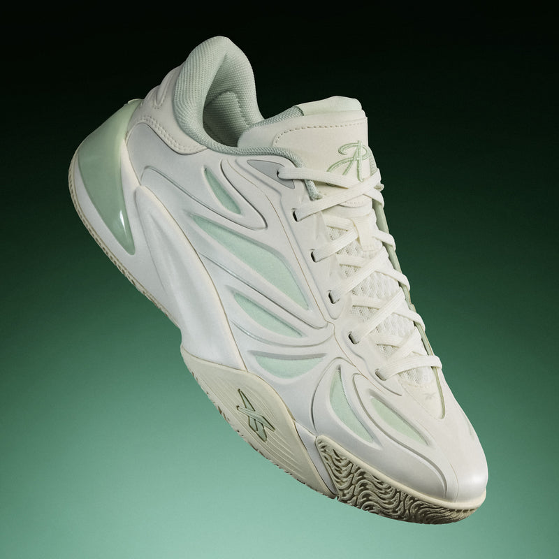 The Reebok Angel Reese 1 Basketball Shoes, featuring a white and light green colorway and a sleek, modern silhouette inspired by performance basketball footwear with innovative technologies like the Energy Return System, are showcased against a green gradient background in both side and top views.