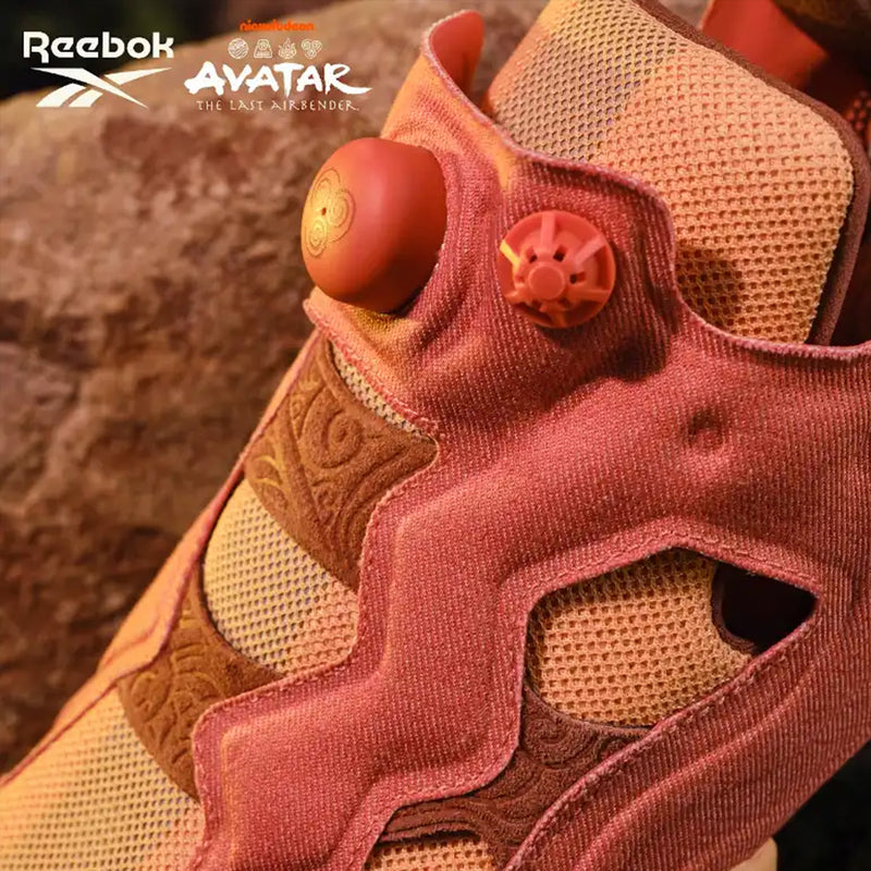 Close-up of a terracotta-colored Reebok x Avatar Instapump Fury 94 slip-on sneaker featuring a pump button on the tongue embossed with a stylized elemental symbol.